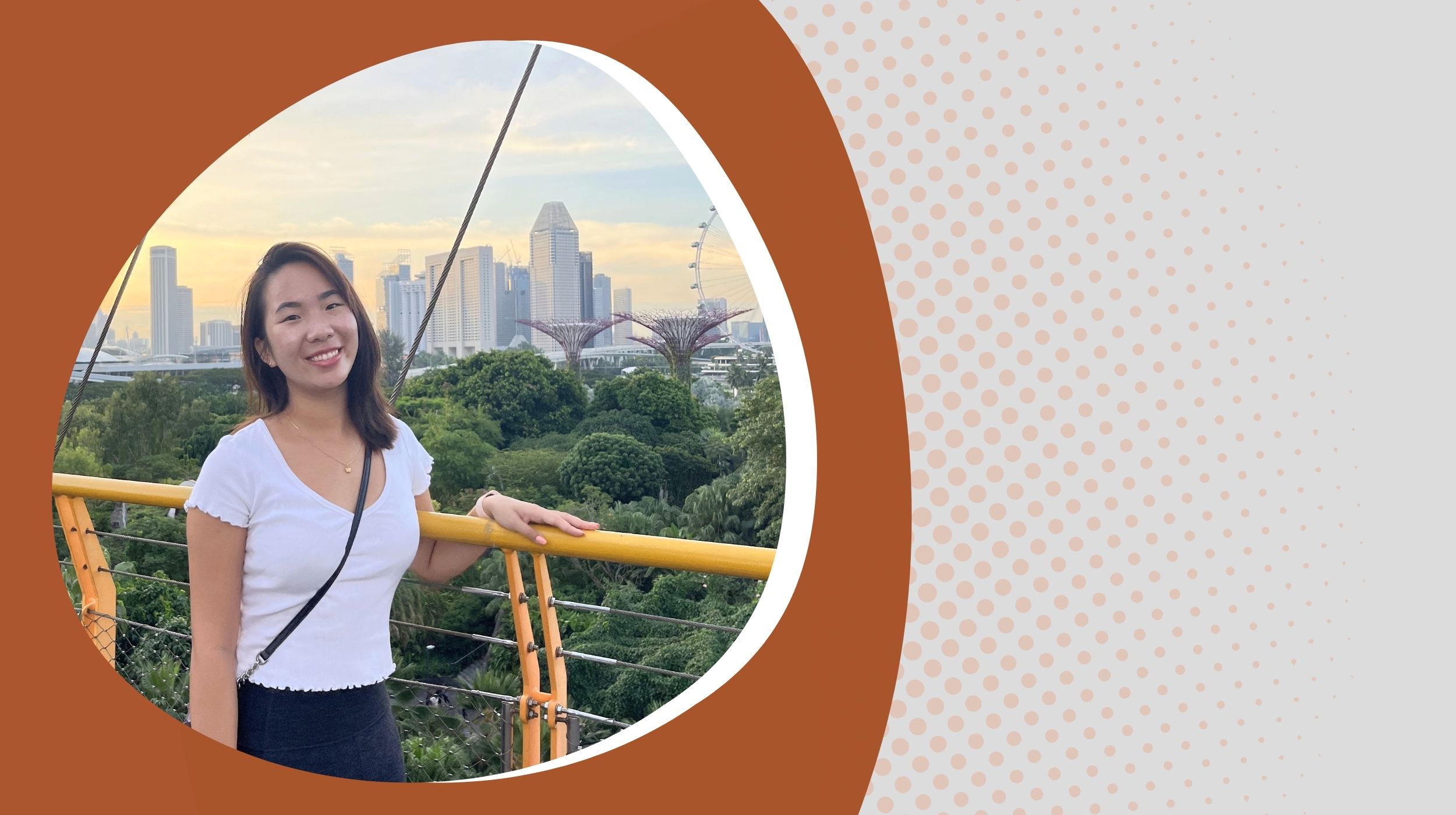Person standing by a yellow railing with a view of modern city buildings and ferris wheel in the background.