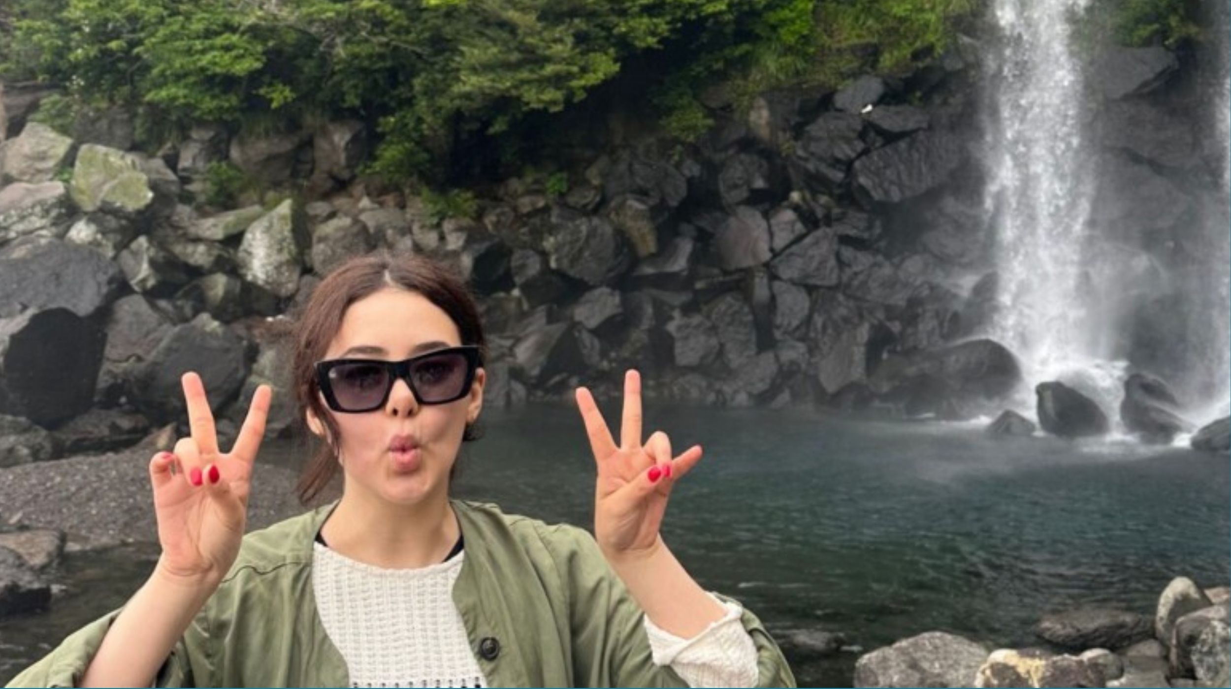 Student with peace fingers in front of waterfall