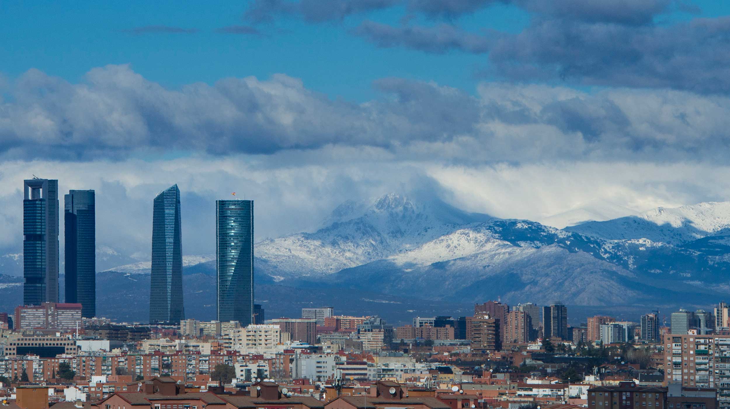 Cityscape view of Financial District, Madrid with snowy mountains on the horizon