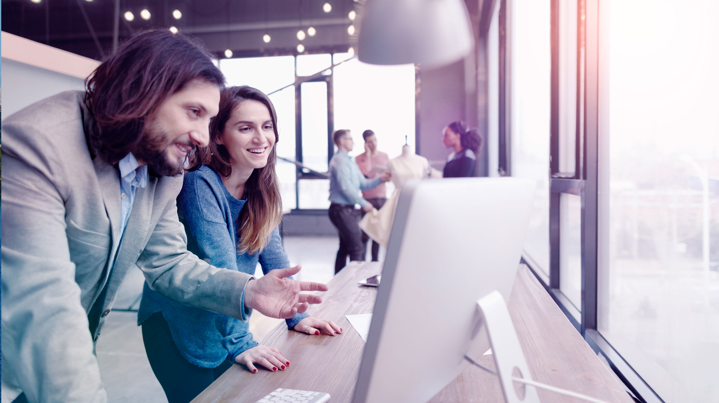 A man and a woman collaborate on a project on the computer.