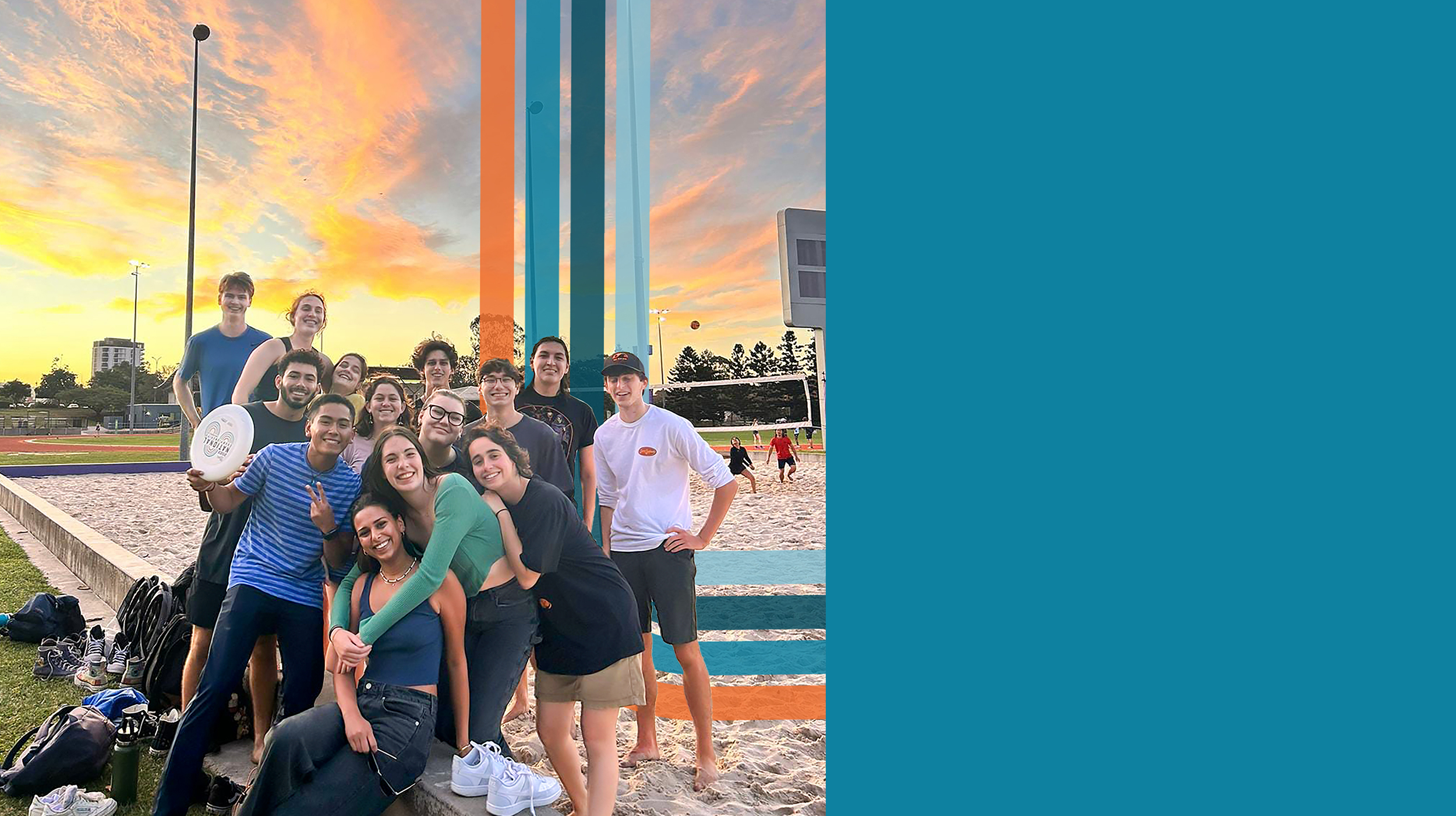 student group posing for photo at sunset on a sandy volleyball court in Australia.