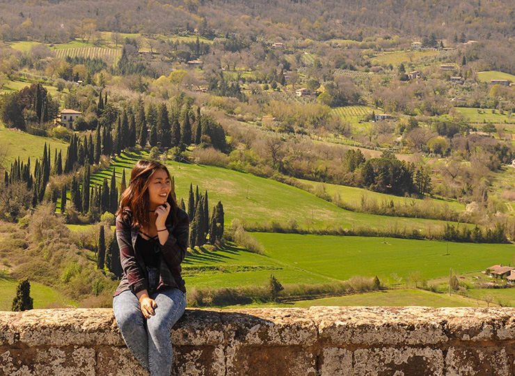 Student sitting on a wall looking over the landscape