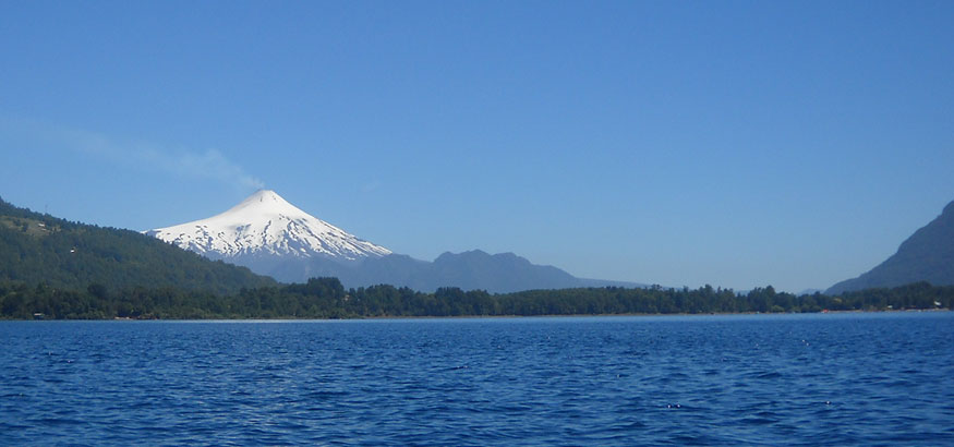The snow covered Volcán Villarrica behind a big blue lake in Villarrica, Chile.