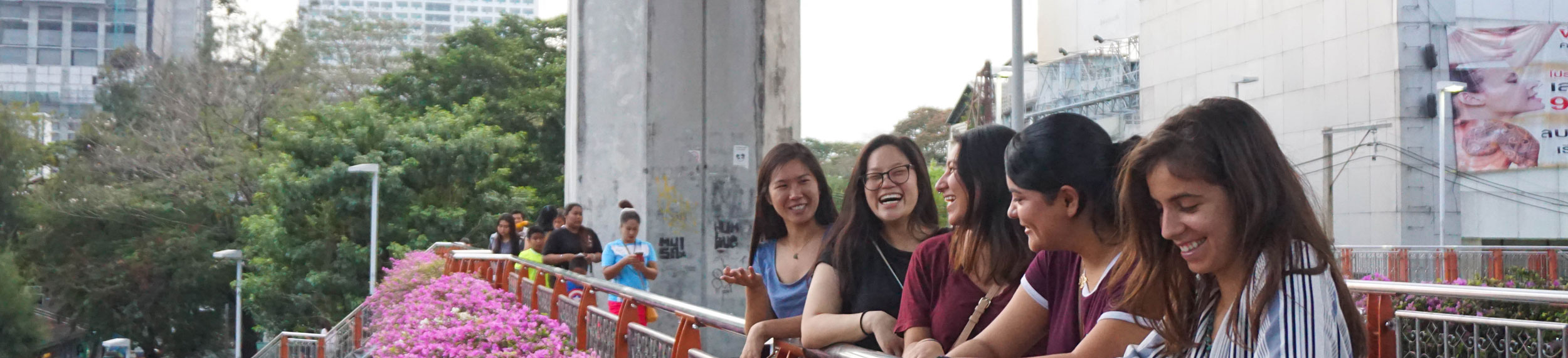 Five students smiling and laughing on a bridge. 