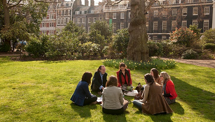 Students and instructor gather for group discussion in sunny London park, England
