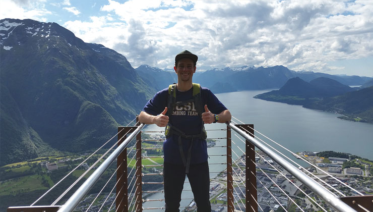 Nolan Pieper of UC Santa Barbara gives the “thumbs up” with a view of mountains and water in the distance in Oslo, Norway.