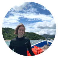 Ronnie Page-Harley smiles for a photo on a boat with a Costa Rica forest in the background. 