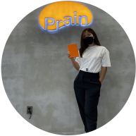Sarah Chun poses for a photo while wearing a mask and holding an orange notebook.