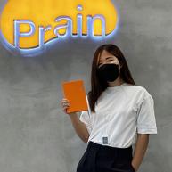 Sarah Chun poses for a photo while wearing a mask and holding an orange notebook.